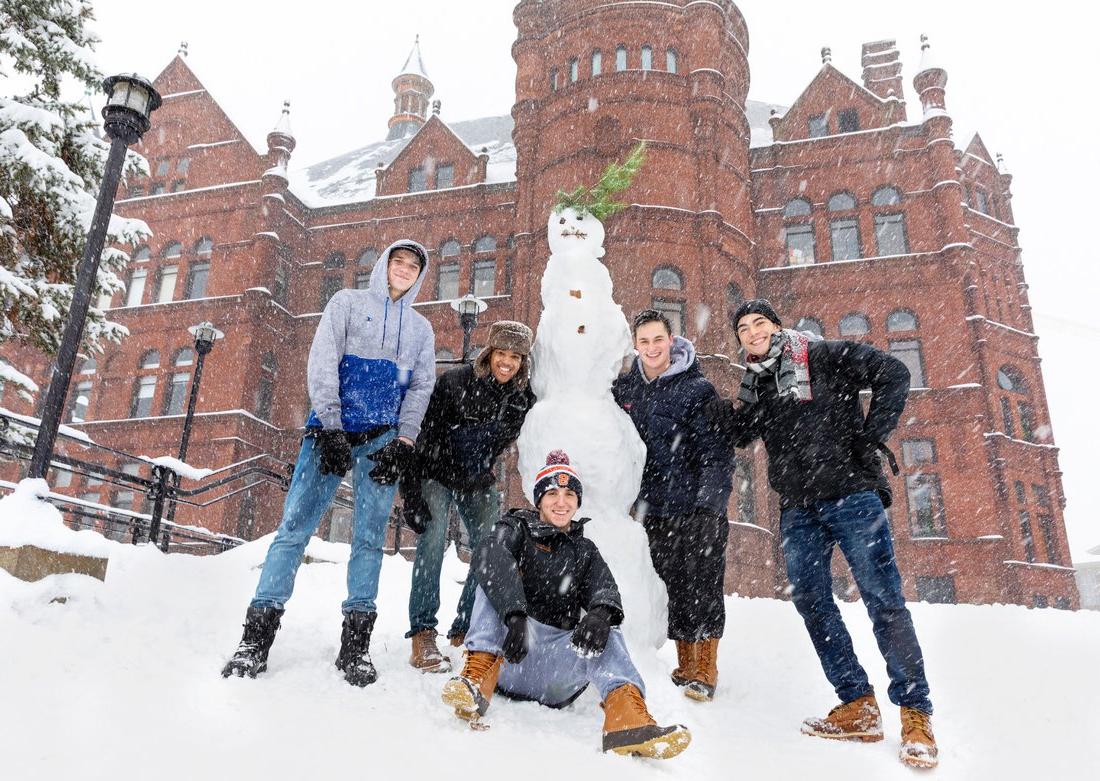 Group of students building a snowman outside on campus.